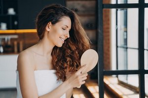 Woman brushing her hair while wearing a white towel